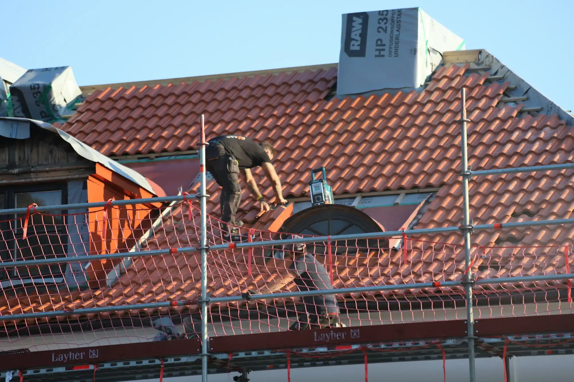 Dachdecker auf einem Ziegeldach mit Gerüst