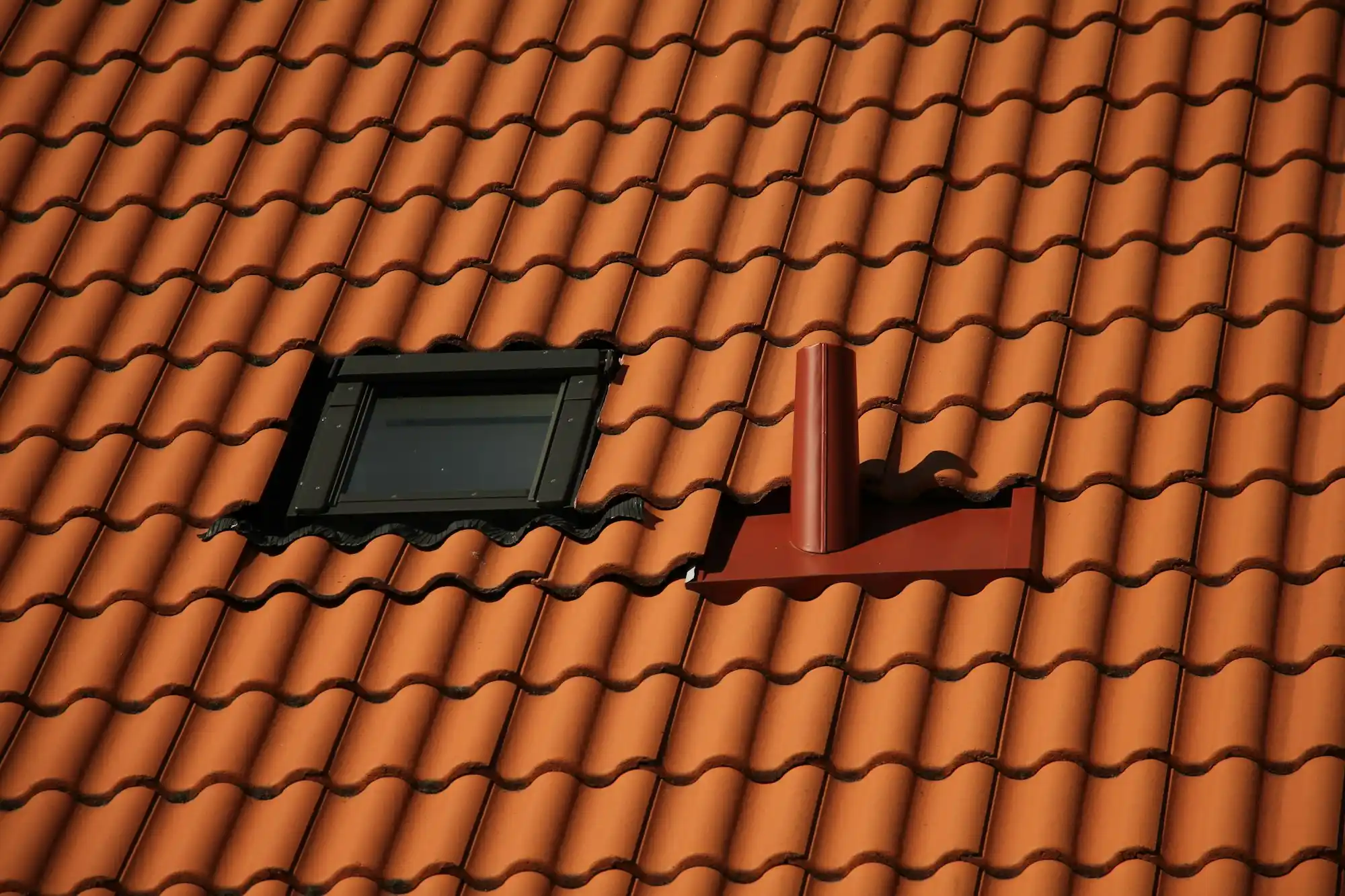 Dachfenster in einem Ziegeldach mit orangefarbenen Ziegeln